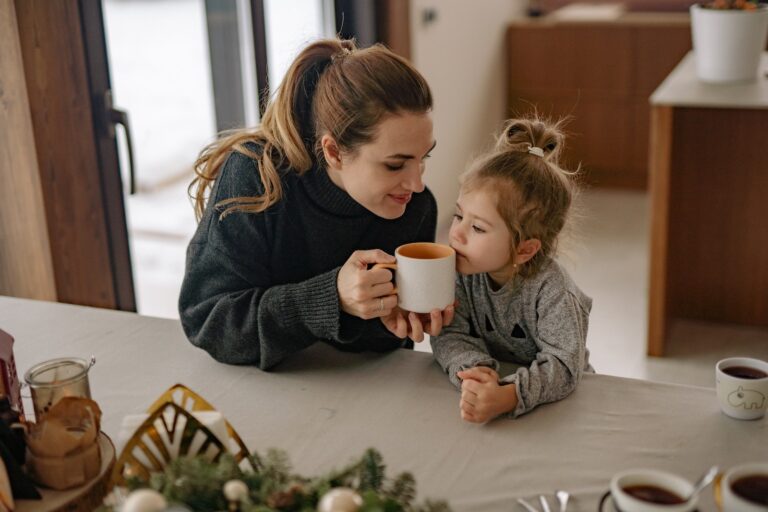 Woman Gives a Cup with Drink to Smell to a Girl Sitting Beside